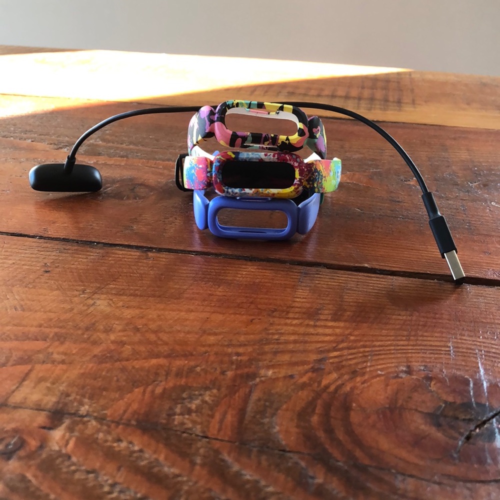 Fitbit with three bands and a charger.